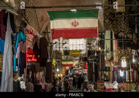ISFAHAN, IRAN - AUGUST 8, 2018: Street of the Isfahan bazar with an Iranian flag hanging, in a covered alley of the market. Symbol of the Persian arch Stock Photo