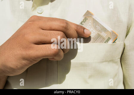Man hand takes a new 500 indian currency note out of his pocket close up Stock Photo