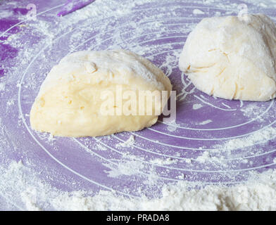 Homemade dough is cut in half on a floured surface Stock Photo
