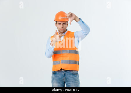 Young handsome architec man with wearing safety helmet over isolated background making frame with hands and fingers with happy face. Creativity and photography concept. Stock Photo