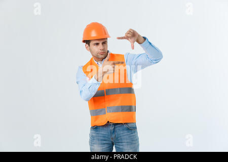 Young handsome architec man with wearing safety helmet over isolated background making frame with hands and fingers with happy face. Creativity and photography concept. Stock Photo