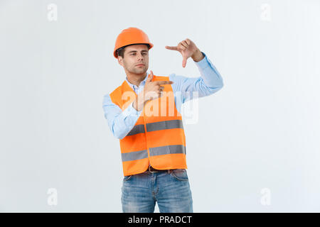 Young handsome architec man with wearing safety helmet over isolated background making frame with hands and fingers with happy face. Creativity and photography concept. Stock Photo