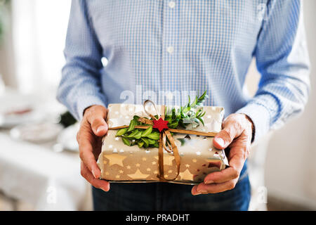 An unrecognizable senior man holding wrapped present at Christmas time. Stock Photo