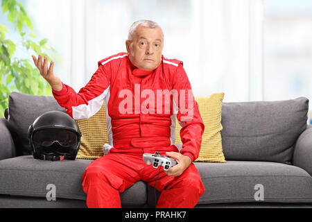 Confused elderly man in a racing suit holding a joystick Stock Photo