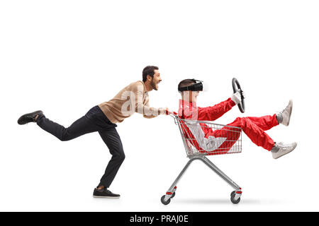 Teenager in a racing suit with VR googles in a shopping cart being pushed by a young man isolated on white background Stock Photo