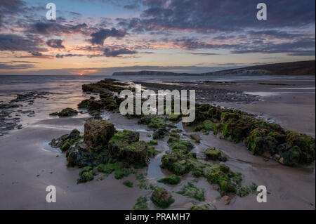 Compton Bay, Isle of Wight, UK. 30th Sept, 2018. A beautiful and atmospheric sunset over the beach and rocks at Compton bay on the Isle of Wight. Cooler autumn weather bringing a cloudy sky and moody feel to the sea and cliffs at low tide. Sunset colours reflected in the wet sands and seaweed covered rocks. Credit: Steve Hawkins Photography/Alamy Live News Stock Photo