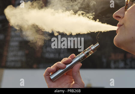 FILED - 31 July 2015, Berlin: A woman smokes an e-cigarette. Alternatives  to conventional cigarettes such as e-cigarettes and tobacco heaters are on  the advance worldwide. This is the conclusion of a