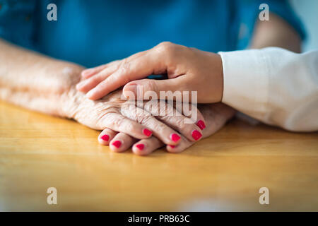 Younger Female Hands Holding Senior Adult Woman Hands. Stock Photo