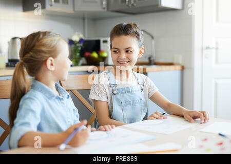 Two little sisters discussing ideas of what to draw while spending weekend at home together Stock Photo