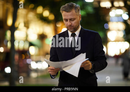 Professional financier looking through papers while walking along street in the evening Stock Photo