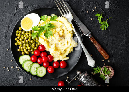 Mashed potato with green peas, tomatoes, cucumber and boiled egg. Potato puree on plate with vegetables and egg Stock Photo