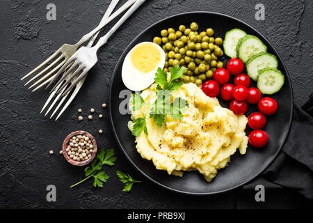 Mashed potato with green peas, tomatoes and boiled egg. Potato puree on plate with vegetables and egg