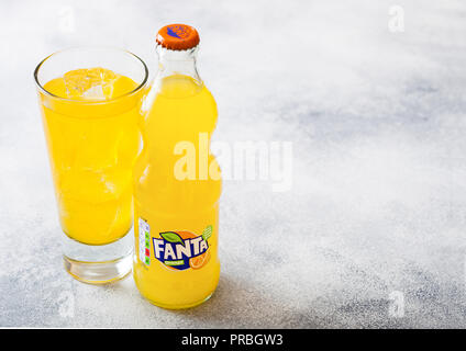 LONDON, UK - SEPTEMBER 28, 2018: Glass and bottle of Fanta Orange soda drink with ice cubes and bubbles on stone kitchen  background. Stock Photo