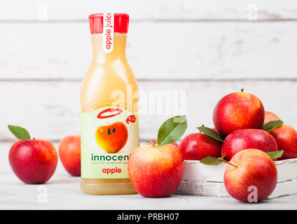 LONDON, UK - SEPTEMBER 13, 2018: Plastic bottle of fresh Innocent Apple Juice with fresh apples in box on wood background. Stock Photo