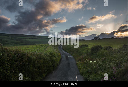 Narrow asphalt road across green farming hills in the coast of Newgale in Wales. UK