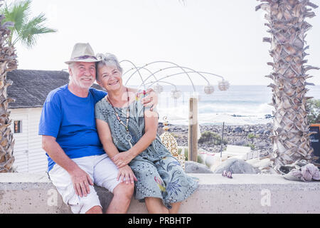 Happy senior couple laughing hugged on a summer day. concept of vacation, relaxation, rest. Behind it as a sea, ocean background Stock Photo