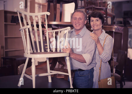 Cheerful couple is shopping the old armchair in the antique store Stock Photo