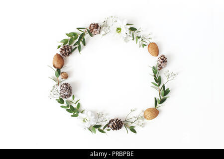 Christmas circle floral composition. Wreath of eucalyptus branches, larch cones, almonds, chrysanthemum and baby's breath flowers on white background. Winter wedding design. Flat lay, top view. Stock Photo