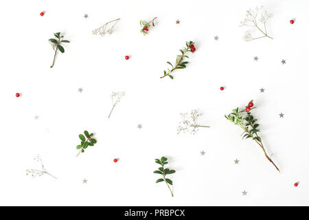 Christmas floral pattern. Winter composition of red cranberry branches, baby's breath flowers and silver confetti stars on white table. Festive background. Flat lay, top view. Stock Photo