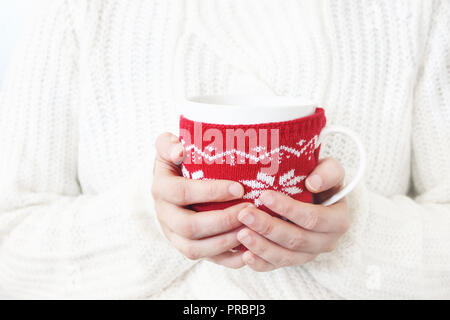 Closeup of woman's hands in white knitted sweater holding cup of coffee. Christmas winter design. Feminine styled stock photo. Nordic design. Stock Photo