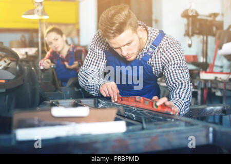 Young man is working with level on his workplace in workshop Stock Photo