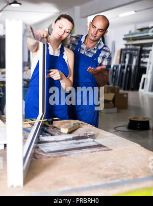 Foreman explaining plastic windows assembly process to young female ...