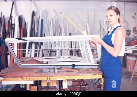 Cheerful positive  woman using measuring tape in her work in production of pvc windows Stock Photo