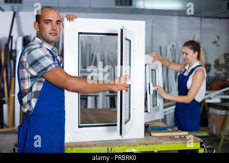 Portrait of  happy male worker with finished plastic window in assembly shop Stock Photo