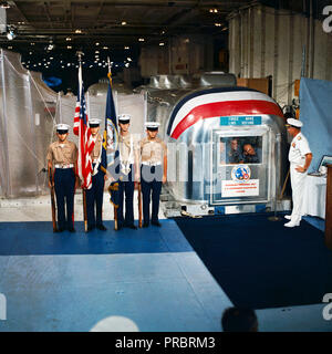 Rear Admiral Donald C. David, Commander, Manned Spacecraft Recovery Force, Pacific, welcomes the crew of the Apollo 12 lunar landing mission aboard the USS Hornet, prime recovery vessel for the mission. A color guard was also on hand for the welcoming ceremonies. Inside the Mobile Quarantine Facility (MQF) are (left to right) astronauts Charles Conrad Jr., commander; Richard F. Gordon Jr., command module pilot; and Alan L. Bean, lunar module pilot. Stock Photo