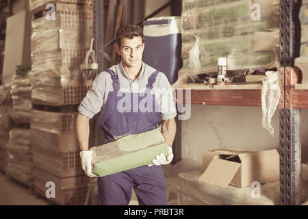 attractive male in uniform is choosing cement in the building store room Stock Photo