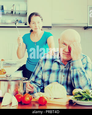 Mature married couple having quarrel at kitchen Stock Photo