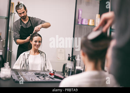 Young woman getting new hairstyle at professional hair styling saloon. Stock Photo