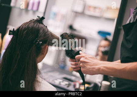 Young woman getting new hairstyle at professional hair styling saloon. Stock Photo