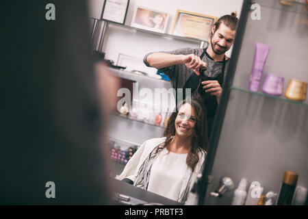 Young woman getting new hairstyle at professional hair styling saloon. Stock Photo