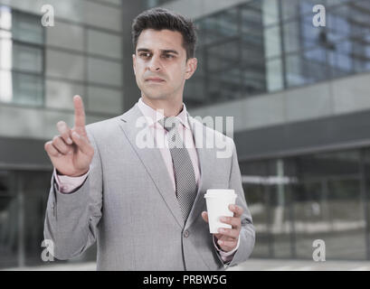 Businessman standing with factory background and touching imaginary virtual screen Stock Photo