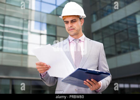 Businessman holding folder with documents and attentively reading Stock Photo