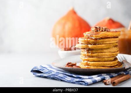 Tasty pumpkin pancakes with nuts and caramel sauce on grey concrete background. Horizonta, copy space for text or recipe, selective focus Stock Photo
