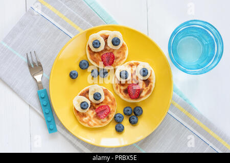 Breakfast pancakes for kids. Funny cute animal shaped pancakes on a yellow plate. Top view. Food art Stock Photo