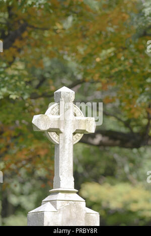 A Celtic cross on a headstone in a New England cemetery in autumn Stock Photo