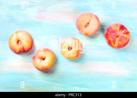 An overhead photo of vibrant organic flat saturn peaches, shot from above on a teal background with copy space Stock Photo
