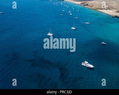 Aerial view of moored boats floating on a transparent sea. Scuba diving and summer holidays. Canary Coast, Lanzarote. Spain Stock Photo