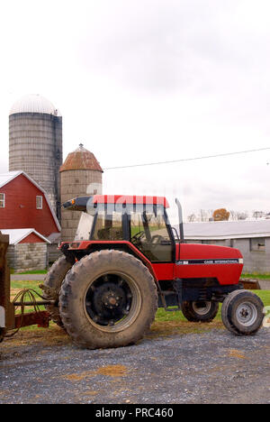 A large Case International Tractor parked in front of silos on a family farm Stock Photo