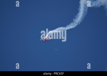 An airliner is visible behind this Extra 330 plane from the french air force making a performance at the Francazal air show near Toulouse. Stock Photo