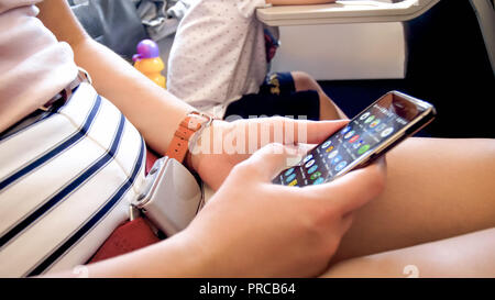 Closeup photo of young woman flying in airplane and using mobile phone Stock Photo