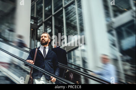 Hipster businessman using escalator in city, travelling to work. Stock Photo