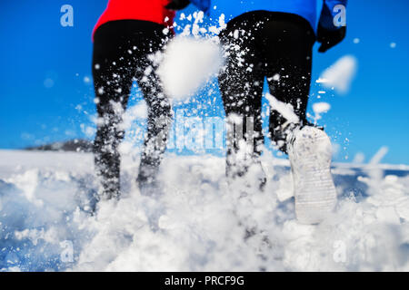 Rear view of legs of senior couple jogging in winter nature. Stock Photo