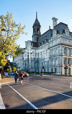 Montreal city hall (L'hotel de ville) and a Canadian couple crossing the street on a sunny summer afternoon in Montreal, Quebec, Canada Stock Photo