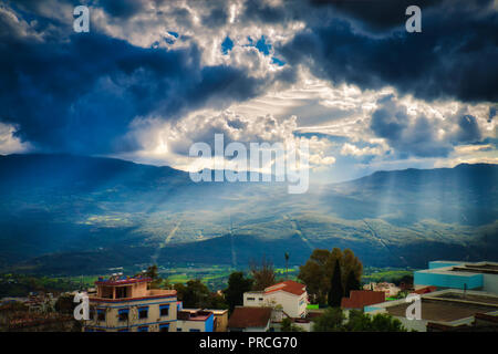 Rays of light go through the clouds illuminating the town of Chaouen on a rainy day Stock Photo
