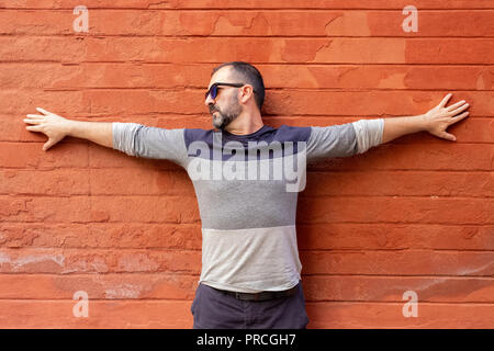 man standing with his arms stretched out in front of the red wall