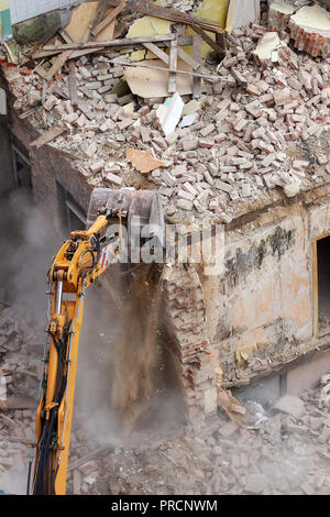 Crushing brick wall, building demolition with an excavator, view from above. Stock Photo